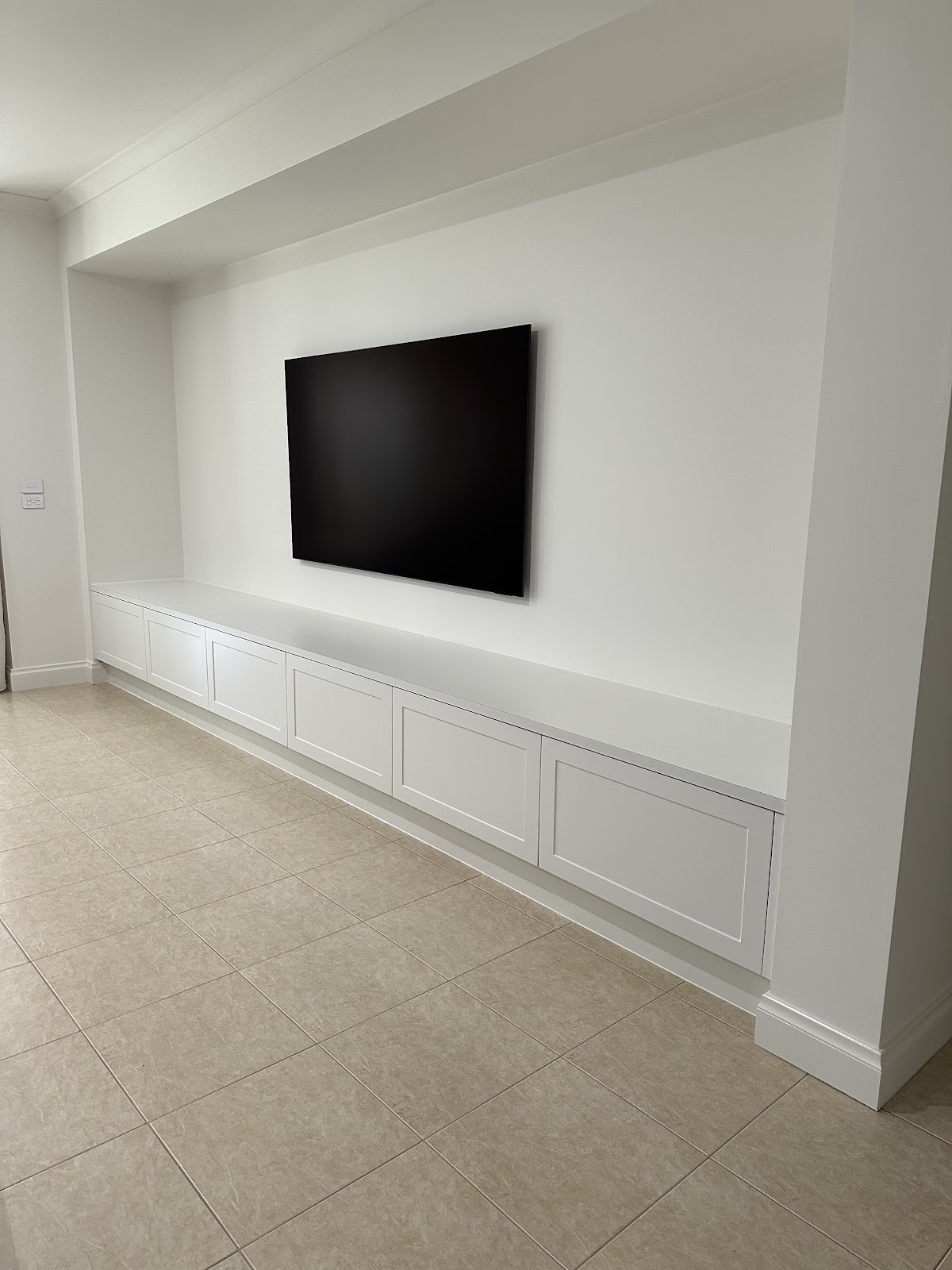 Long white shaker-style storage unit under a wall-mounted TV