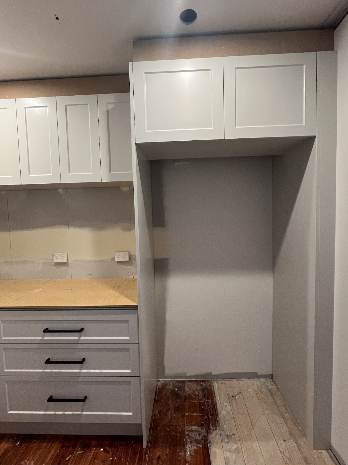 White shaker cabinetry with black handles during installation