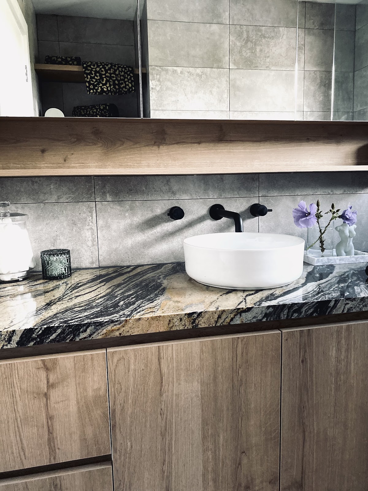 Timber-grain vanity with a veined stone top, round basin and a floating shelf